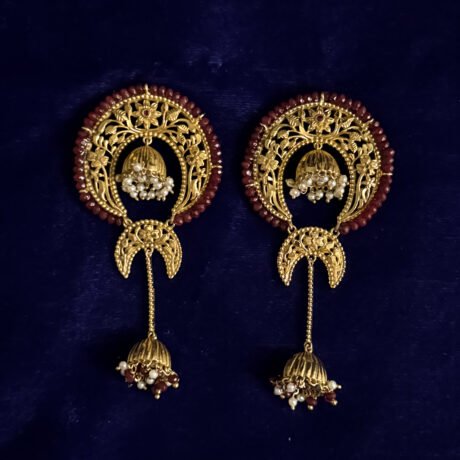 Introducing our Dual Half Chand Jhumko Earrings, a stunning tribute to Bengal’s rich jewellery heritage. These earrings celebrate traditional Hand Naksha artistry, blending classic motifs with a modern silhouette that flatters every look. While designing these earrings, we kept in mind the heritage—Bengal handcrafted Naksha with flower motifs and a beautiful dangling Jhumko decorated with real Pearls and Ruby beads. The result is a statement piece that reflects both cultural elegance and contemporary refinement. Lightweight, festive, and intricately detailed, the Dual Half Chand Jhumko Earrings are perfect for weddings, celebrations, and heritage-inspired styling. A timeless addition to every jewellery lover’s collection.